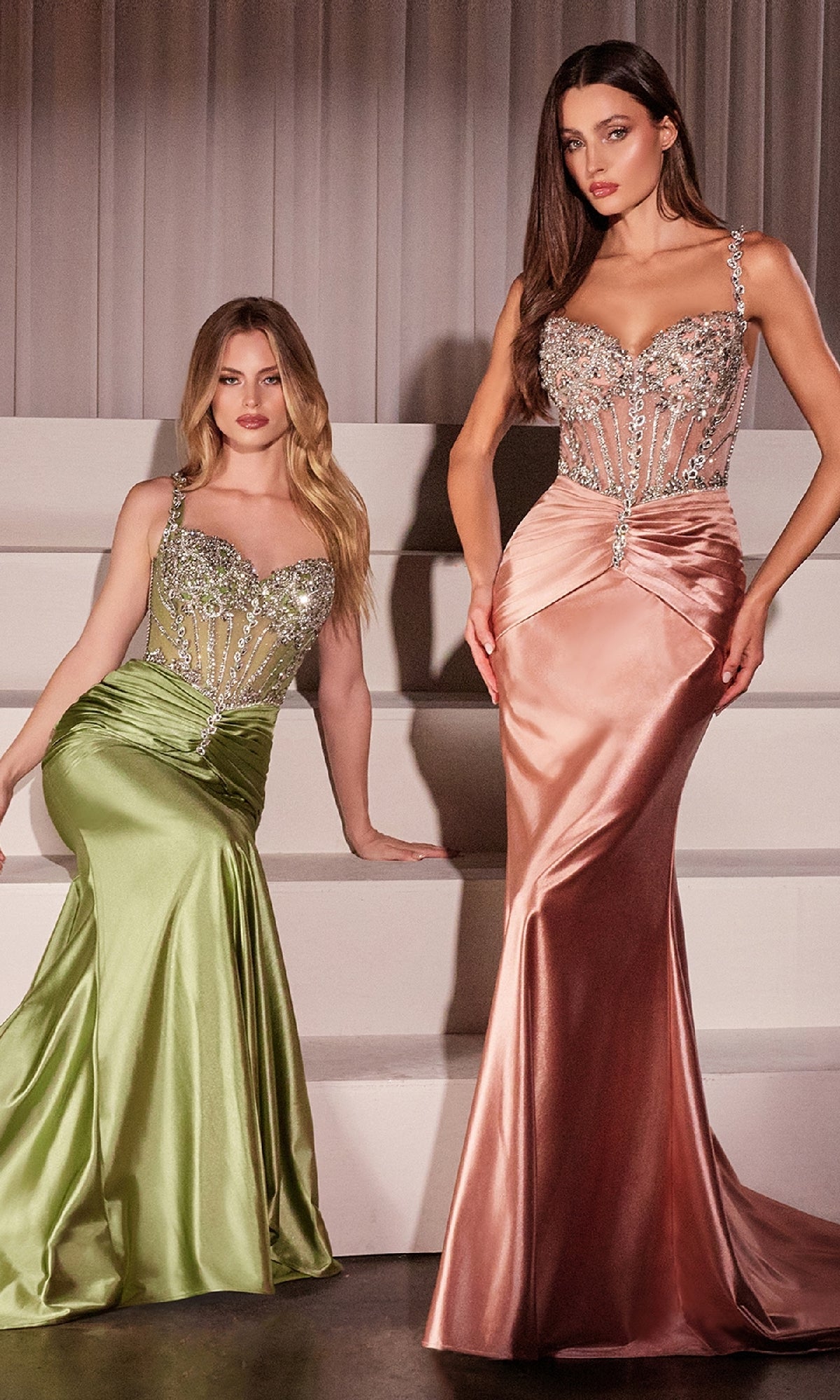 Two women stand gracefully by white stairs in elegant evening gowns: one wears the Ladivine CD757 Crystal-Bodice Long Prom Dress in light green satin, while the other wears a similar style in light pink.